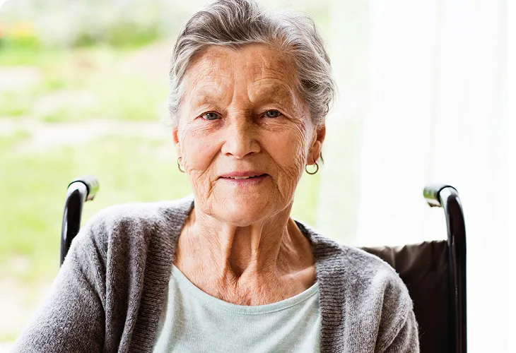An elderly woman in a wheelchair smiling