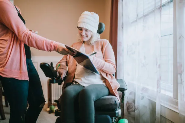 A person in a wheelchair signing a form smiling