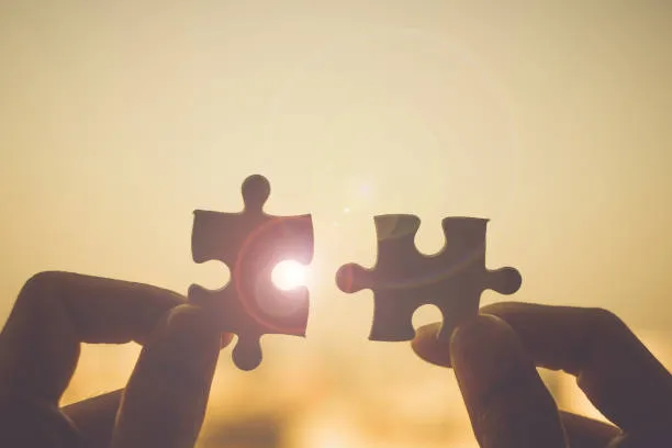 Two hands putting together two puzzle pieces